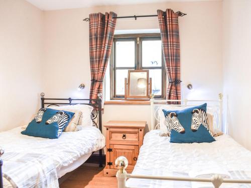 two beds in a room with a window at Riverbank Cottage-uk42229 in Low Borrowbridge