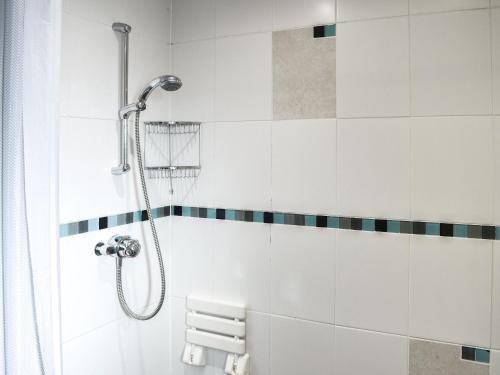 a shower in a bathroom with white tiles at Riverbank Cottage-uk42229 in Low Borrowbridge