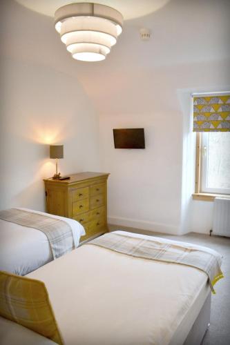 two beds in a room with a lamp and a dresser at The ‘Servants Quarters@Delny House’ in Invergordon