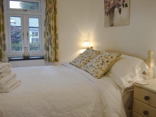 a bedroom with a white bed and a window at Ivy Cottage in Henllan