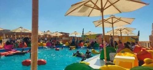 eine Gruppe von Personen in einem Pool mit Sonnenschirmen in der Unterkunft مصيف بلطيم 