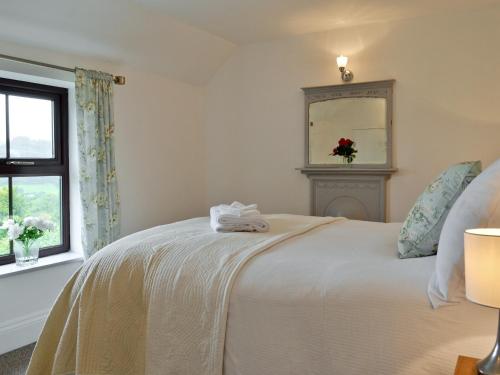 a white bed in a room with a window at Gwar Nant Cottage in Ystrad-ffin