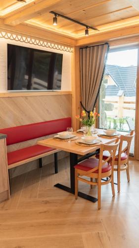 a dining room with a table and a bench at Apartamenty Osada Biała Woda Szczawnica Jaworki in Szczawnica