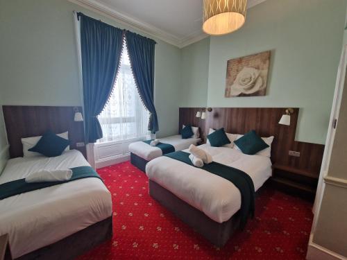 a hotel room with two beds and a red carpet at Lyndon Guesthouse in Dublin