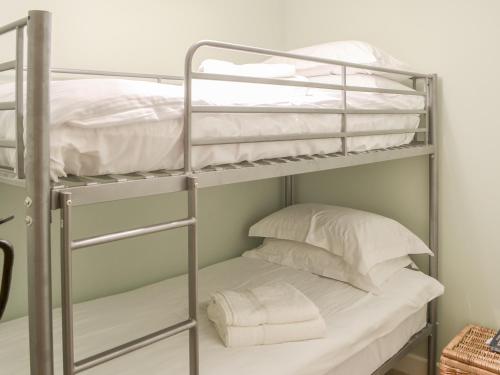 Addycombe Cottage في روثبيري: سرير بطابقين مع الوسائد البيضاء في الغرفة