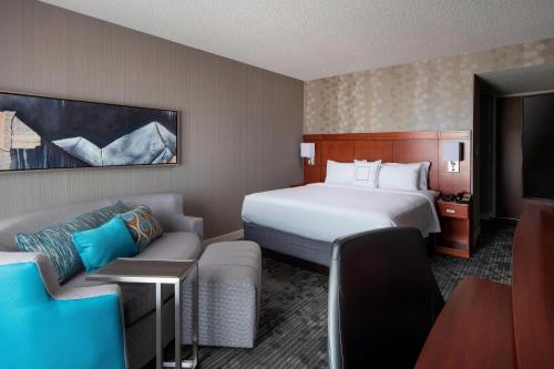 a hotel room with a bed and a couch at Courtyard by Marriott Denver Airport in Denver