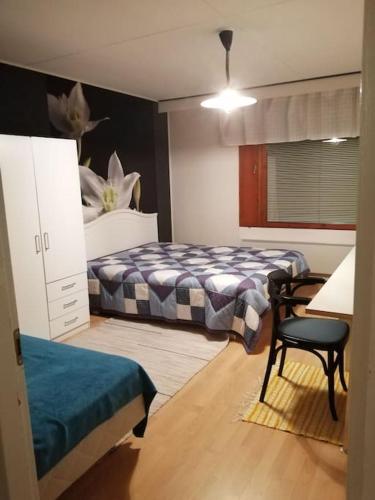 a bedroom with two beds and a table and a chair at Tilava kahden makuuhuoneen asunto pihalla in Kauhajoki
