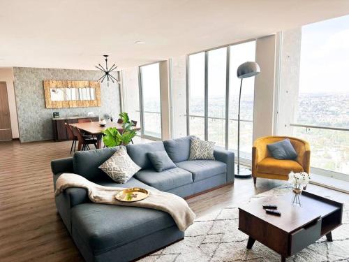 ein Wohnzimmer mit einem blauen Sofa und einem Tisch in der Unterkunft Luxury 4BR Apartment w Pool, Spa & Stunning Views in Puebla