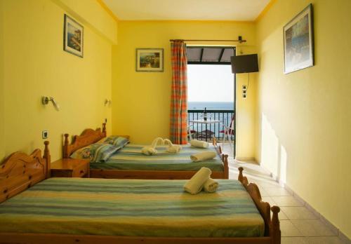 two beds in a room with a view of the ocean at STROUBIS STUDIOS 2 in Megás Limniónas