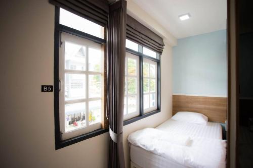 una piccola camera da letto con un letto e due finestre di Sclass HOME Private, Central old city (Wholehouse) a Chiang Mai
