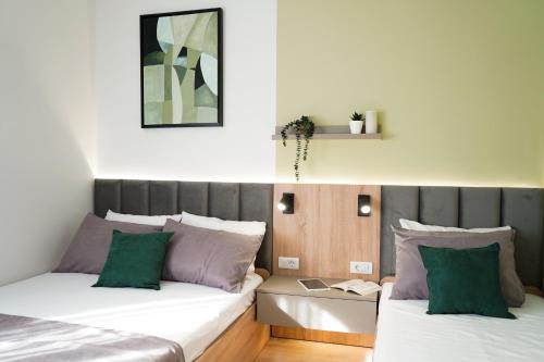 1 Schlafzimmer mit 2 Betten mit grünen und violetten Kissen in der Unterkunft Tolevski Apartments, Bitola in Bitola
