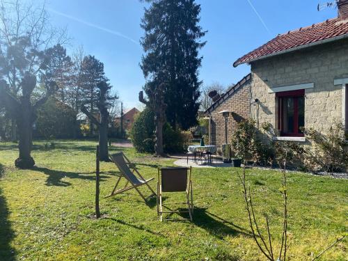 a yard with a chair in front of a house at Studio épicéa avec jardin dans charmante propriété in Méry-sur-Oise