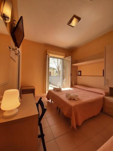 a bedroom with two beds and a desk and a window at Hotel Originale by ALEhotels in Rimini