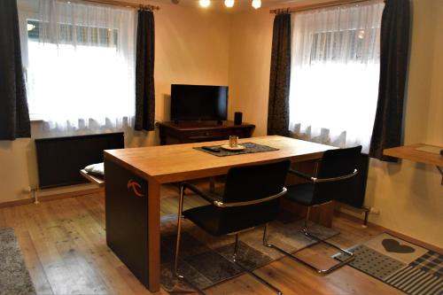 een woonkamer met een houten tafel en 2 ramen bij Ewald's Panoramablick in Feldkirchen in Kärnten