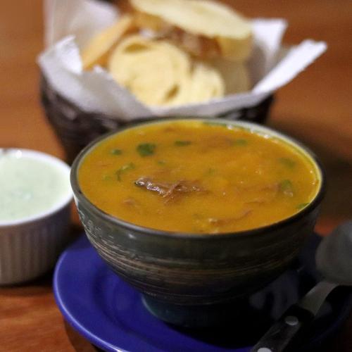 a bowl of soup on a blue plate with bread at Jacarandá Palace Hotel in Teixeira de Freitas