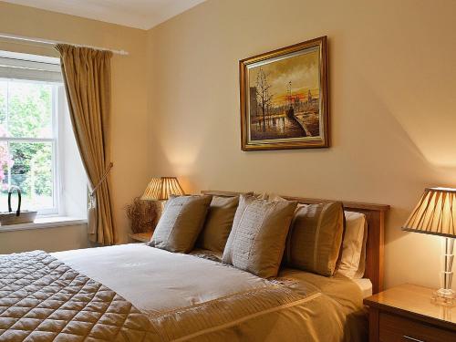 een slaapkamer met een bed met 2 lampen en een schilderij bij Ladybird Cottage in Lochend