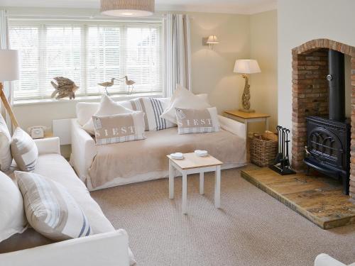 a living room with a white couch and a fireplace at Maison De Quai in Cley next the Sea