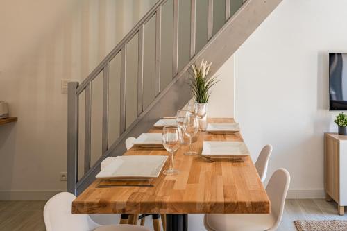 a long wooden table with chairs and wine glasses at Le noé in Caen