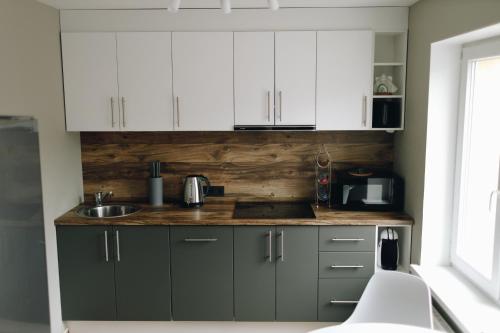 a kitchen with white cabinets and a sink at LK Apartment in Rēzekne