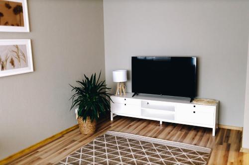 a living room with a flat screen tv on a white cabinet at LK Apartment in Rēzekne