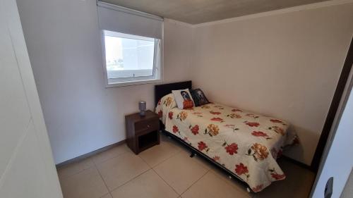 a small bedroom with a bed and a window at Departamento Marina Horizonte II in Coquimbo