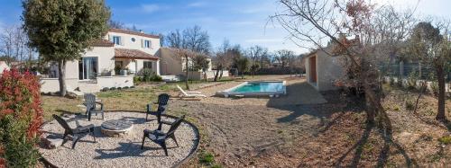 a backyard with a pool and chairs and a house at Le JARDIN DES DELIS gite NEUF avec piscine bio UV in Saint-Saturnin-les-Apt