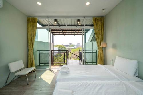 a bedroom with a large white bed and a balcony at Sclass Townhome, 5 min from Night Market old city in Chiang Mai