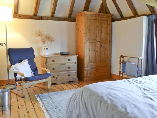 a bedroom with a bed and a chair and a dresser at Hawthorne Cottage in Preston