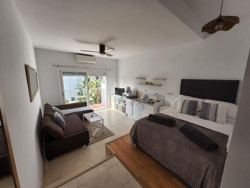 a bedroom with a bed and a couch and a kitchen at Tranquility studio apartment in Estepona