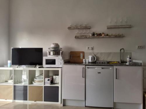 cocina con armarios blancos y microondas en Tranquility studio apartment en Málaga