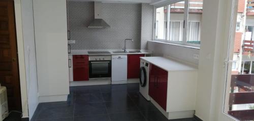 a kitchen with red and white cabinets and a sink at Apartamento BELA VISTA in Sanxenxo