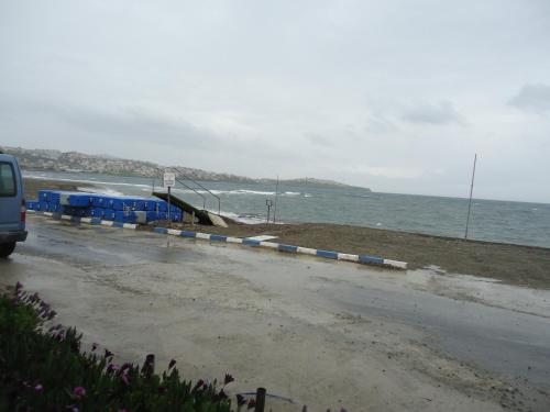 a beach with blue and white barriers and the ocean at Bells Motel in Seferihisar