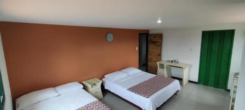 a bedroom with two beds and a clock on the wall at Finca la castellana in Quimbaya