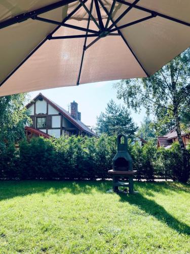 un ombrello in un cortile con una panchina nell'erba di Happy House - Kaszubska Ostoja a Barkocin