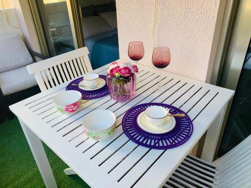 un tavolo bianco con piatti viola e bicchieri di vino di Butterfly-Palais des Festival-center-quiet-AC-Wi Fi parking a Cannes
