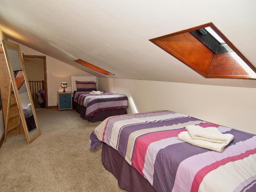 een slaapkamer op zolder met 2 bedden en een dakraam bij St Andrews Barn in Necton