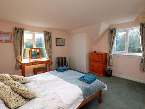 a bedroom with a bed and a desk and windows at Mountain Cross in Gatehouse of Fleet