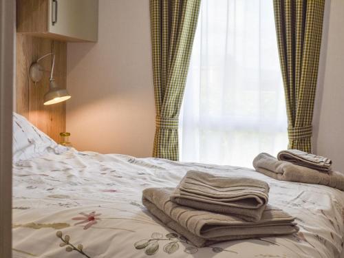 a bed with towels on it with a window at The Willows in Stonham Aspall