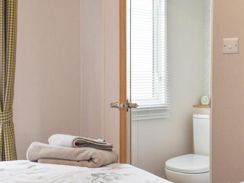 a bathroom with a toilet and towels on a bed at The Willows in Stonham Aspall