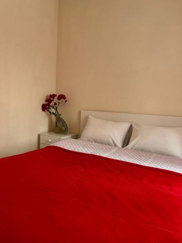 a red blanket on a bed with a vase with flowers at Козацькі Забави in Rivne