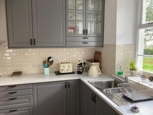 a kitchen with white cabinets and a sink at Kilpatrick Glebe in Crossabeg