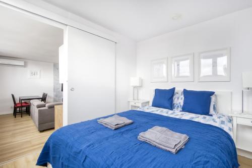 een witte slaapkamer met een blauw bed met blauwe kussens bij Central Family Apartment in Warschau