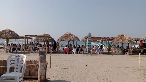a beach with some straw umbrellas and a group of people at Hotel La Intimidad in Antón Lizardo