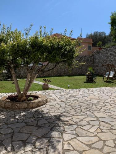 a stone patio with a tree in the middle at Lofos house in Karavadhos