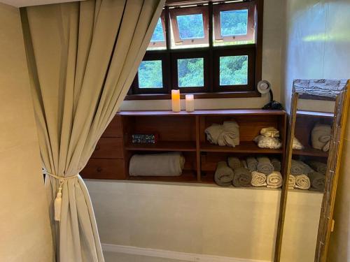 a bathroom with a window and a shelf with towels at Recanto de Itaipava - casa com forno de pizza a lenha, churrasqueira, pet friendly, equipada para até 6 pessoas, em meio à Natureza e próxima ao centro do bairro in Petrópolis