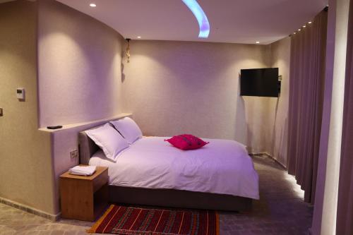a bedroom with a bed with a red pillow on it at Bhalil Farm House in Sefrou