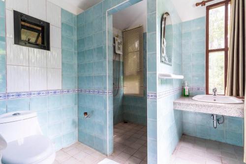 a blue tiled bathroom with a toilet and a sink at Zen MaeKampong Waterfall Villa in Ban Huai Kaeo
