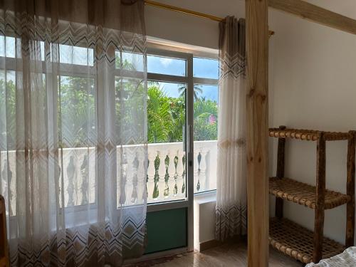 a bedroom with a large window with curtains at Kijiji House Paje in Paje