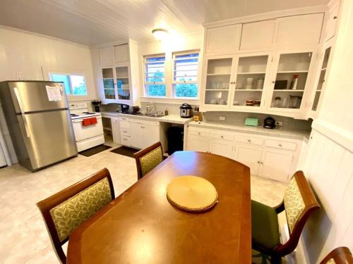 uma cozinha com uma mesa de madeira e um frigorífico em YOUR HILO HOMEBASE - Lovely 3 Bedroom in Heart of Hilo with AC! em Hilo