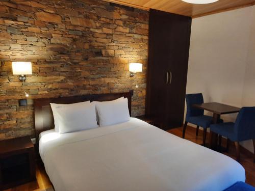 una camera con un grande letto e un muro di mattoni di Casa da Eira de Cima a Chão Sobral